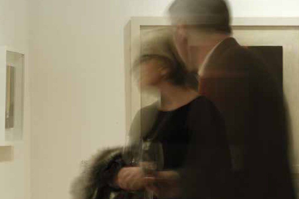 photograph in the bokeh style of two visitors admiring art in a gallery