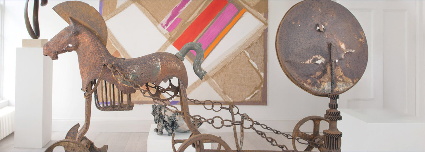 Bronze horse and chariot abstract sculpture in front of a white, orange, pink, read and beige wall art piece