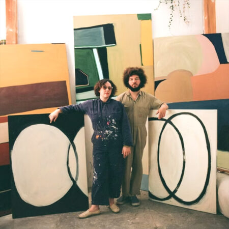 Sara Marlowe Hall and Matthew Zuk pose with Hall's large canvases in her bright studio