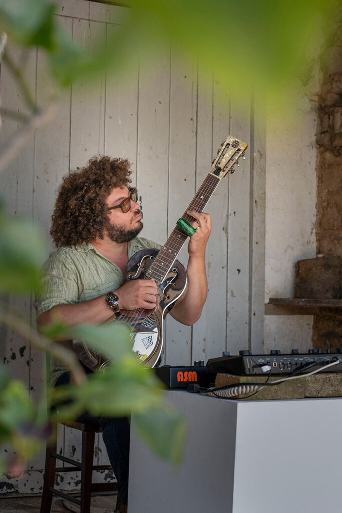Zuk Zuk playing his guitar outside in performance
